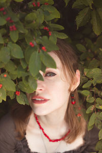 Close up woman peeking through winterberry leaves portrait picture