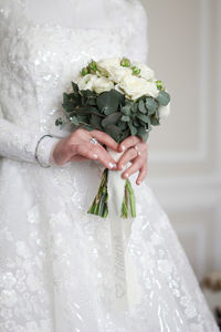 Midsection of bride holding bouquet