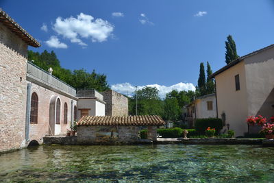Houses by buildings against sky