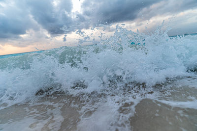 Waves splashing on shore against sky