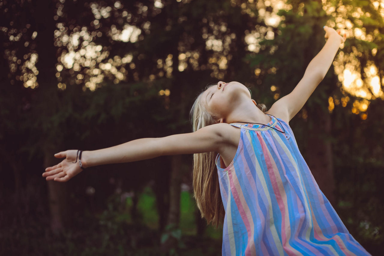 one person, real people, arms outstretched, outdoors, leisure activity, tree, focus on foreground, fun, day, happiness, childhood, lifestyles, nature, smiling, young women, young adult