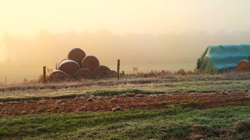 Hay bales on field against sky during sunset