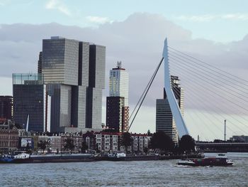 City by river and buildings against sky