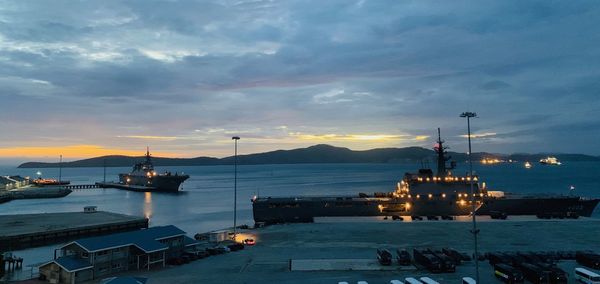 Boats moored at harbor against sky during sunset