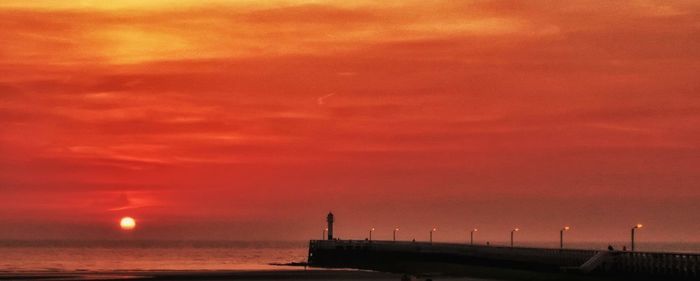 Scenic view of sea against dramatic sky during sunset