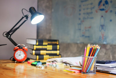Illuminated of school supplies by illuminated lamp on table