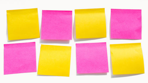 Close-up of yellow and pink adhesive notes on white background