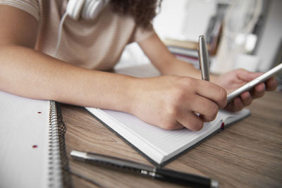 Midsection of woman using smart phone on table