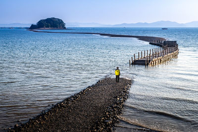 Rear view of man on pier over sea against sky