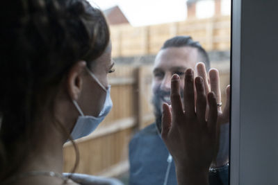 Close-up portrait of woman holding glass window