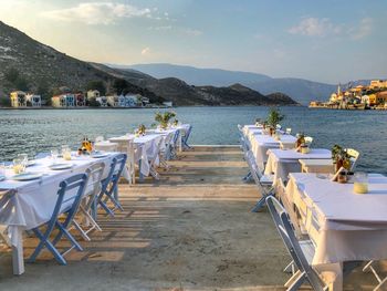 Chairs and table at beach against sky