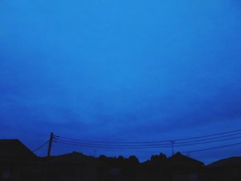 Low angle view of silhouette buildings against blue sky