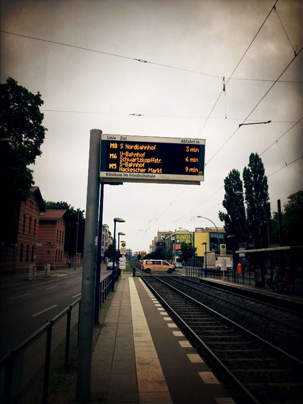 railroad track, rail transportation, railroad station, transportation, public transportation, railroad station platform, text, train - vehicle, communication, built structure, power line, architecture, western script, mode of transport, information sign, travel, passenger train, public transport, building exterior, railway station