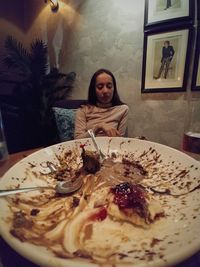 Portrait of young woman with ice cream in plate at home