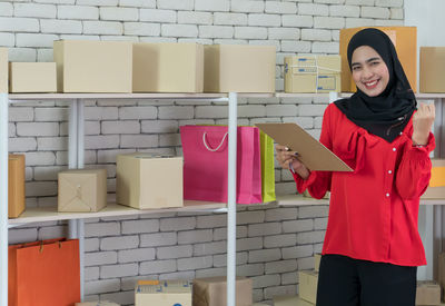 Portrait of a smiling young woman standing against wall