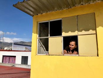 Man looking through window during sunny day