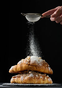 Baked croissants on a black wooden board sprinkled with powdered sugar