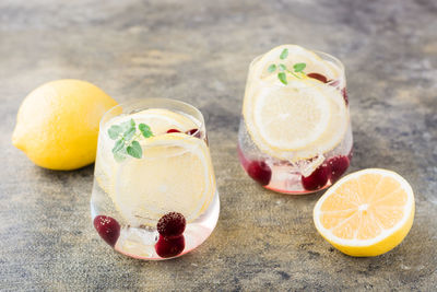 Summer refreshing cold cocktail with lemon, lemon balm and cherry - hard seltzer in glasses 