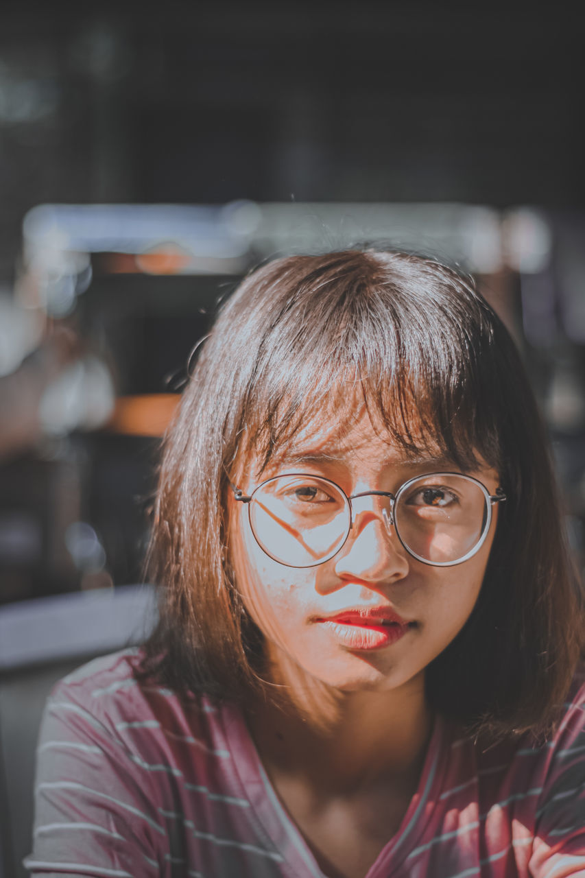 portrait, one person, glasses, headshot, women, front view, eyeglasses, looking at camera, adult, female, vision care, person, child, hairstyle, focus on foreground, childhood, human face, red, casual clothing, lifestyles, young adult, indoors, brown hair, looking, serious, close-up, emotion, fashion