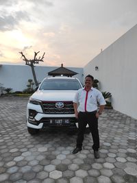 Full length portrait of man standing on car against sky