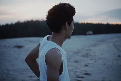 Side view of man standing beach against sky during sunset