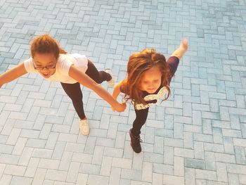 Portrait of happy woman with arms raised on cobblestone