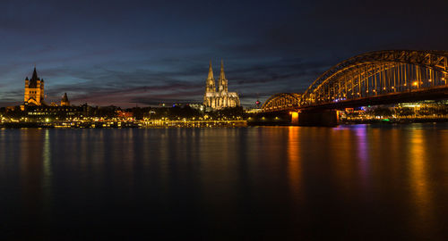 Illuminated bridge over river at night