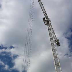 Low angle view of crane against cloudy sky