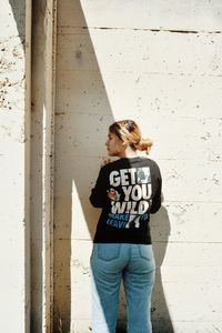 Woman standing by text on wall