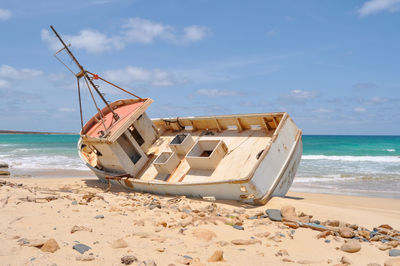 Nautical vessel on beach against sky