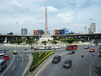 Vehicles on road in city against sky