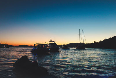 Silhouette boat sailing in sea against clear sky during sunset