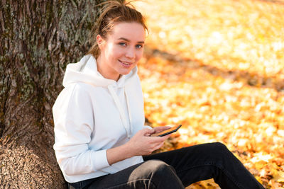 Portrait of smiling young woman using mobile phone