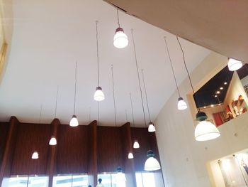 Low angle view of illuminated lighting equipment hanging on ceiling