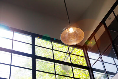 Low angle view of illuminated light bulb hanging from ceiling