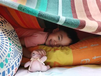 High angle view of avboy hiding on bed at home