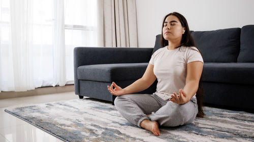 Young woman meditating at home