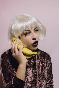 Portrait of young woman using banana as telephone