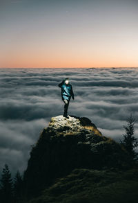 Man standing on rock against sky during sunset