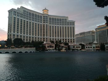 View of buildings by river against sky in city