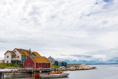 Houses by sea against sky