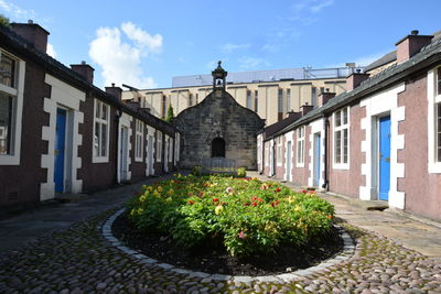 Footpath amidst houses and buildings against sky