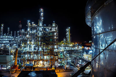 Illuminated factory against sky at night