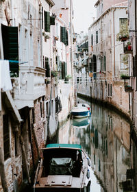 Boats moored in canal amidst buildings in city