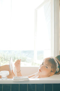 Portrait of woman painting while sitting in bathtub