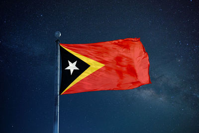Low angle view of east timor flag against star field sky