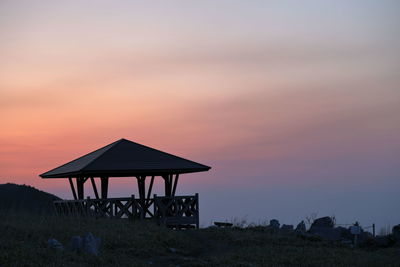 Silhouette built structure on sea against sky at sunset