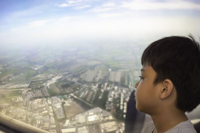 Portrait of boy looking at cityscape against sky