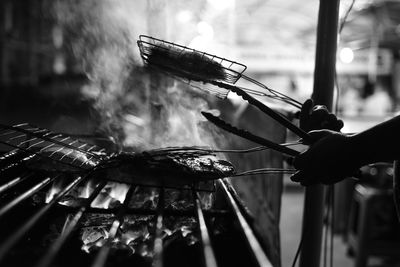 Cropped image of silhouette vendor grilling food in market