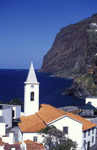 Bell tower in town by sea against clear sky